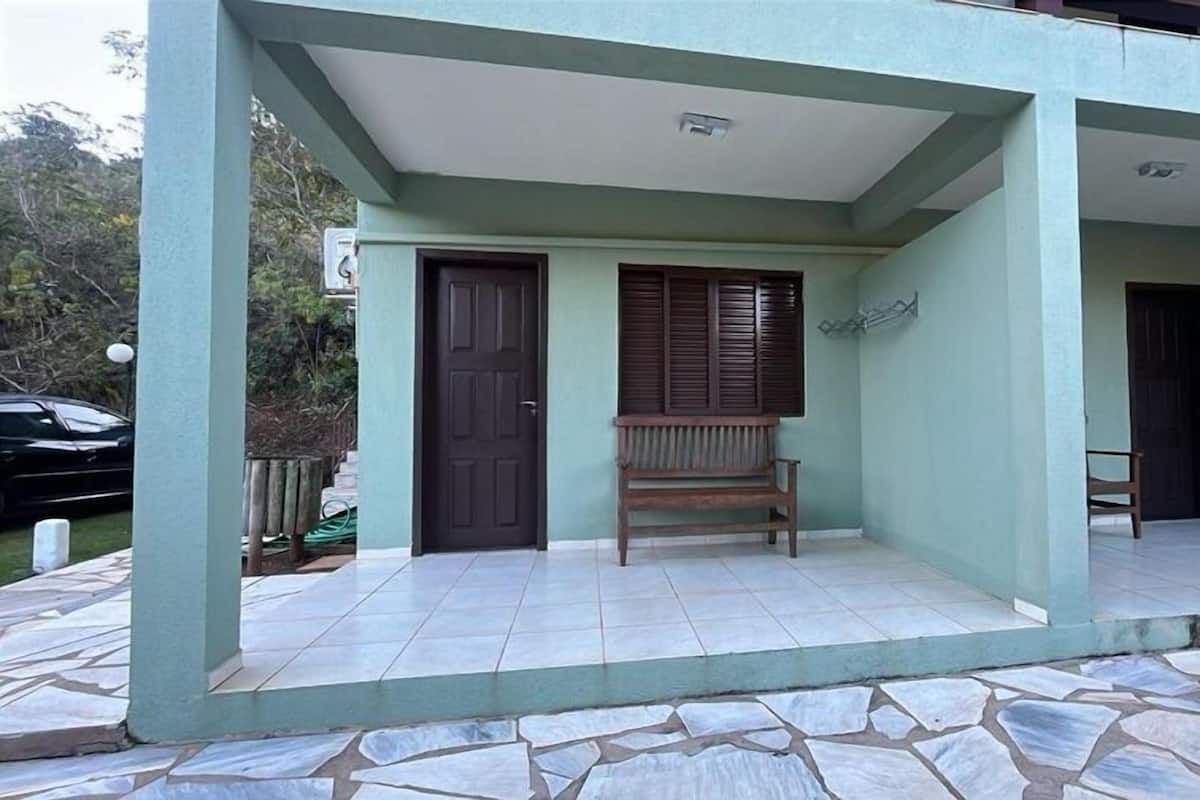 Un porche cubierto con un banco, una puerta y una ventana con contraventanas.