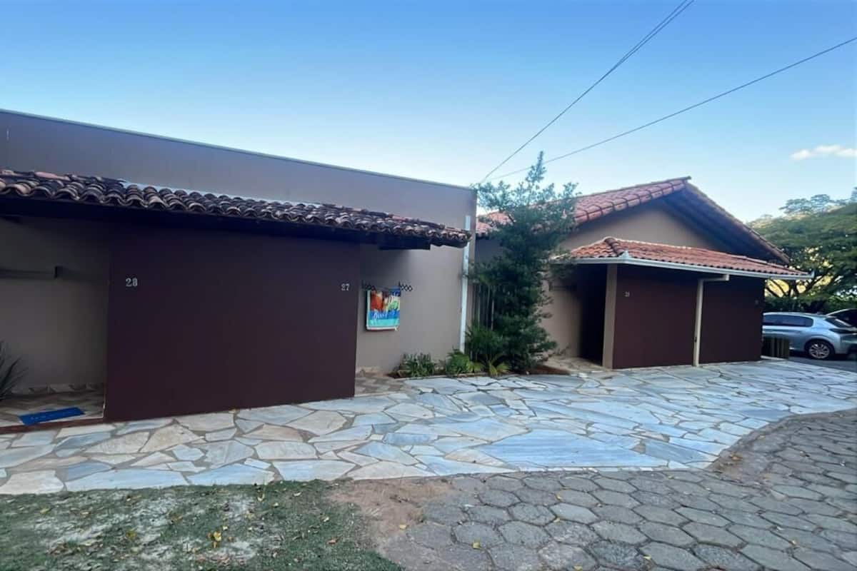 Una casa de dos pisos con techo de tejas, número 27, y un pequeño jardín con pavimento de piedra.