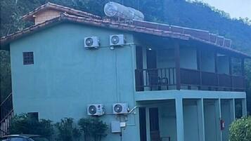 A two-story building with a flat roof, air conditioning units, a satellite dish, and a car parked in front.