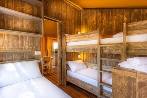 Een eenvoudige houten kamer met stapelbedden, een kleine tafel en een stoel.