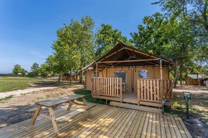 Een houten hut met een veranda, een picknicktafel en een onverharde ondergrond.