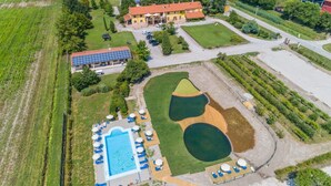 Vue aérienne d’un hôtel doté d’une piscine, de chaises longues et d’un grand bâtiment équipé de panneaux solaires.