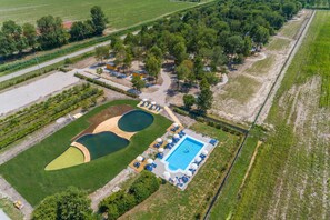 Luchtbeeld van een resort met een zwembad, tennisbanen en een golfbaan.