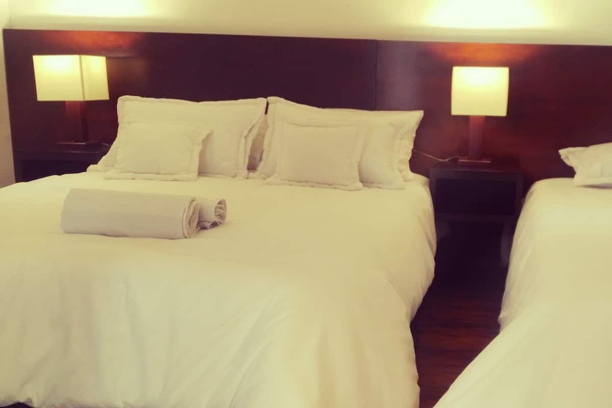 Ein Hotelzimmer mit zwei Betten, jeweils mit weißer Bettwäsche und Kissen, sowie Nachttischlampen.