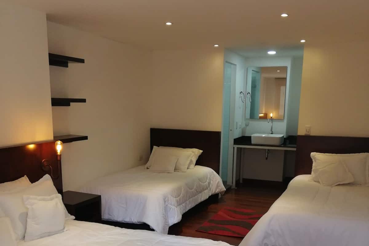 Ein Hotelzimmer mit zwei Einzelbetten, einem kleinen Schreibtisch mit Spiegel und einem roten Teppich.
