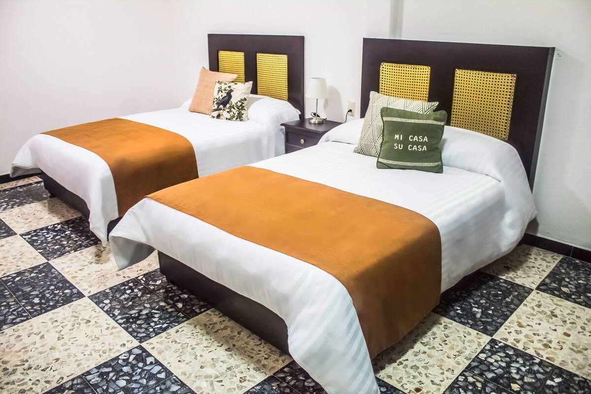 Two beds with headboards, a nightstand, and a patterned floor.