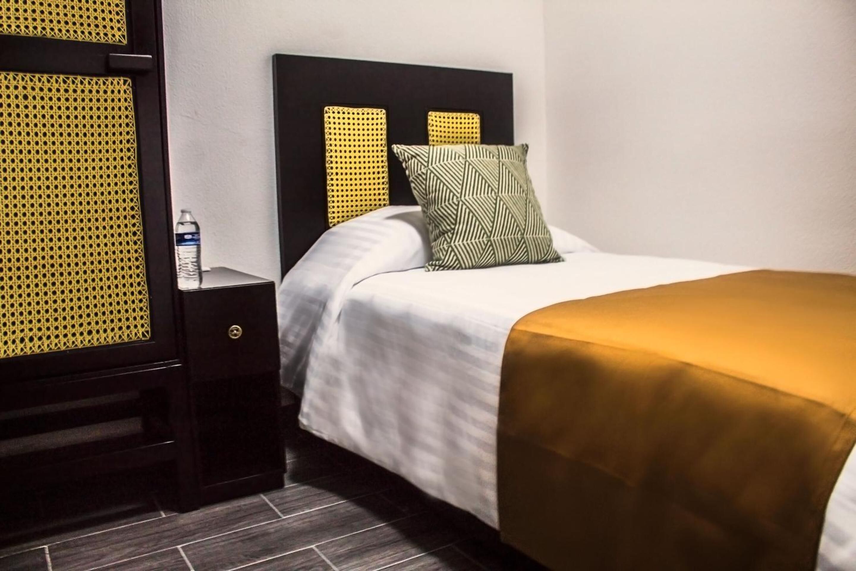 A hotel room with a bed, a nightstand, and a wall unit.