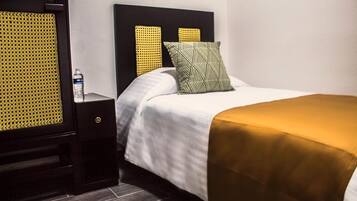 A hotel room with a bed, a nightstand, and a wall unit.