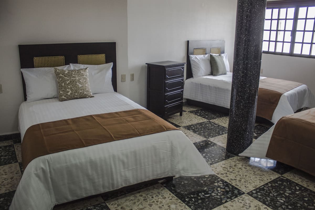 A hotel room with two beds, a dresser, and a window with a view.