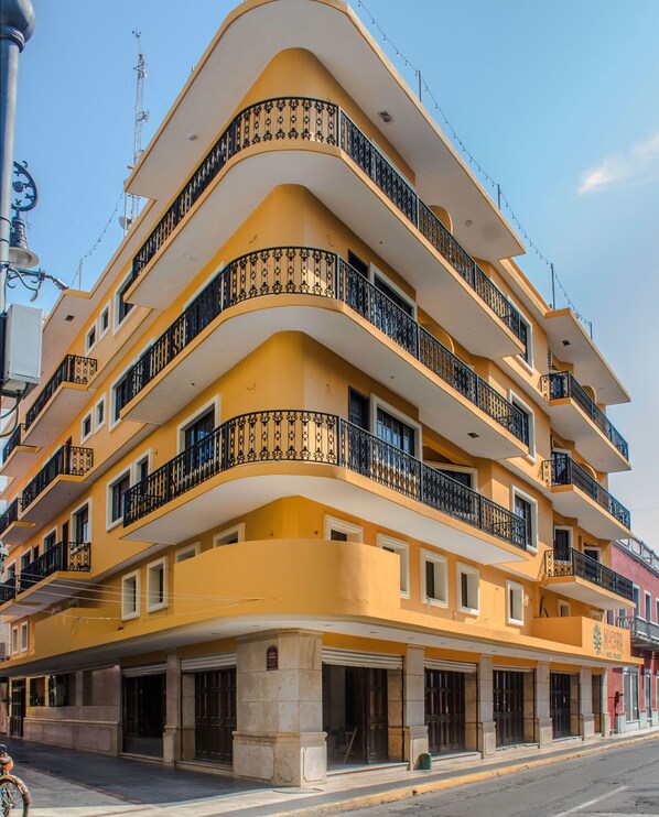 A multi-story building with balconies, a street in front, and a clear sky.