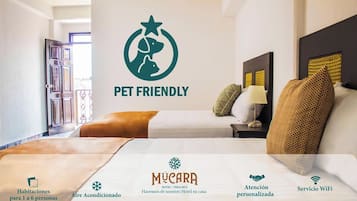A pet-friendly hotel room with a bed, nightstand, and pillows. It includes amenities like air conditioning, personalized attention, WiFi service, and cable TV.