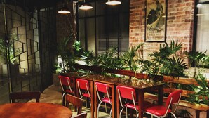 A restaurant interior with brick walls, wooden tables, and red chairs. - Hotel Museo San Moritz (Bogotá)