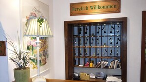 A reception desk with a lamp, a welcome sign, and a key display. - Hotel Froschkönig (Kassel)