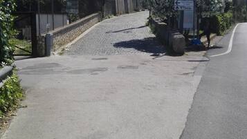 A paved road with a stone staircase leading to a building with a bell tower. There are street signs and a utility pole with wires.