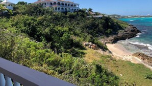 A coastal property with a large white building featuring multiple balconies, surrounded by dense greenery and a beach. - Patricks Bay Villa (Island Harbour)