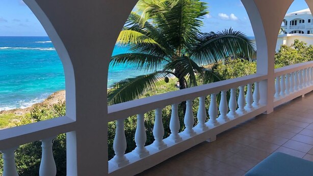 A balcony with a view of the ocean and palm trees. - Patricks Bay Villa (Island Harbour)