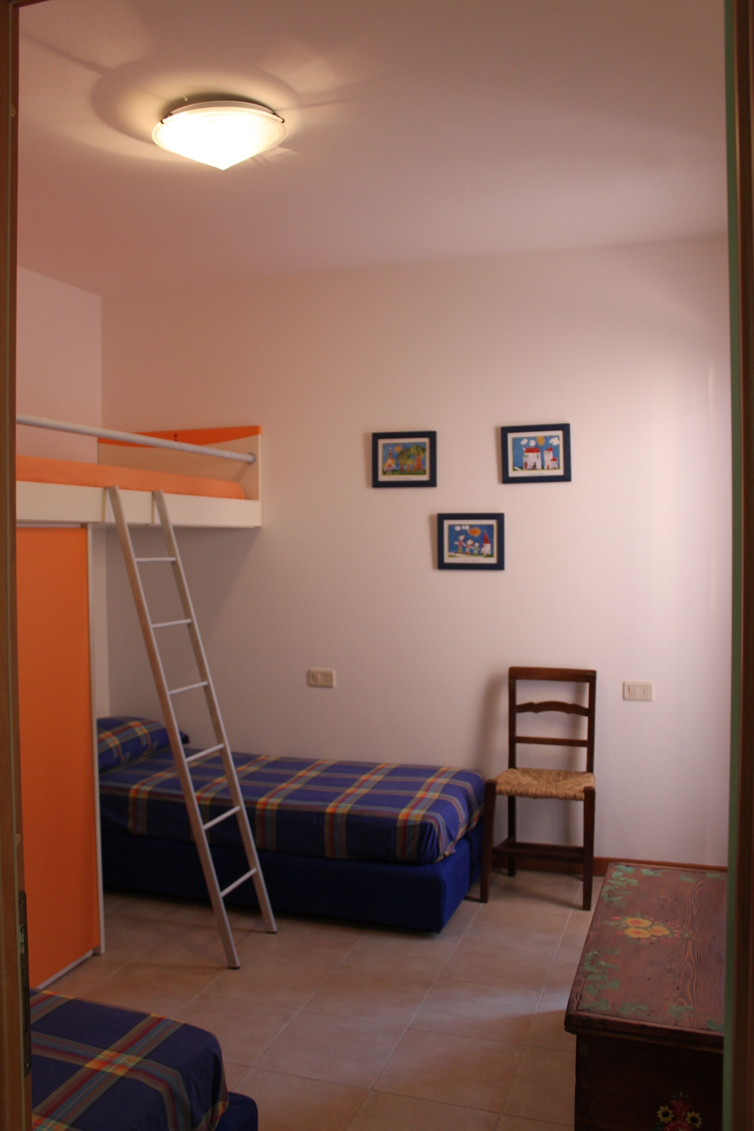Ein Zimmer mit Etagenbetten, einer Leiter, einem Stuhl und einem kleinen Tisch.