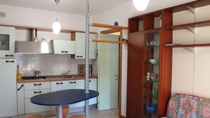 Eine kleine Küche mit Esstisch, Barhocker und integriertem Schrank.