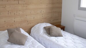 A room with two beds, wooden walls, a small bedside table, and a window. - Cozy 2BR apt for 6 in Peyragudes with ski access (Peyragudes)