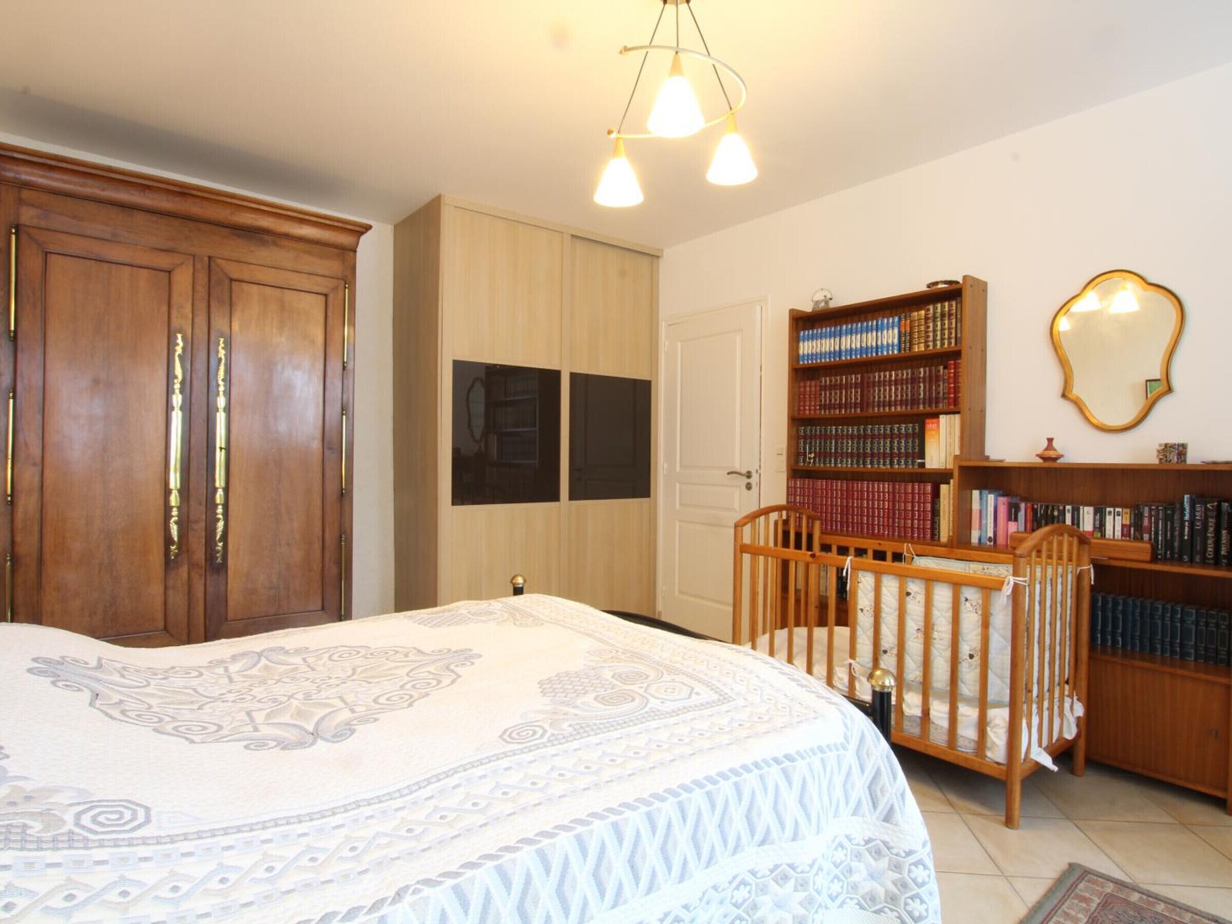 Ein Schlafzimmer mit einem großen Bett, einem Holzschrank und einem Bücherregal.