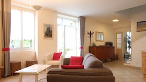 A living room with a sofa, a white table, a red chair, and a wooden cabinet.