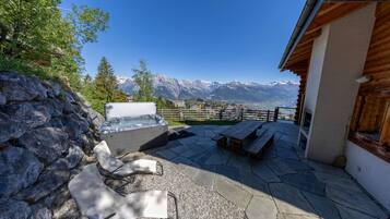 Eine Terrasse mit Steinboden, einem Whirlpool und Holzmöbeln.