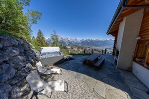 Eine Terrasse mit Steinboden, einem Whirlpool und Holzmöbeln.