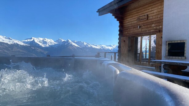 A wooden building with a view of snow-capped mountains.