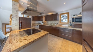 A modern kitchen with granite countertops, stainless steel appliances, and dark wooden cabinets.