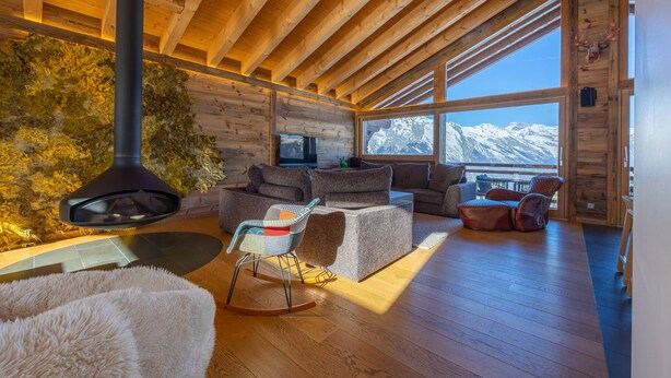 A cozy cabin interior with a stone fireplace, wooden ceiling beams, and a view of snow-capped mountains. - Grimpeur luxury duplex, Spa Access, in front of th (Haute-Nendaz)