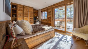A wooden bedroom with a bed, a desk, and a chair. There is a large window and a view of the outdoors. - Grimpeur luxury duplex, Spa Access, in front of th (Haute-Nendaz)