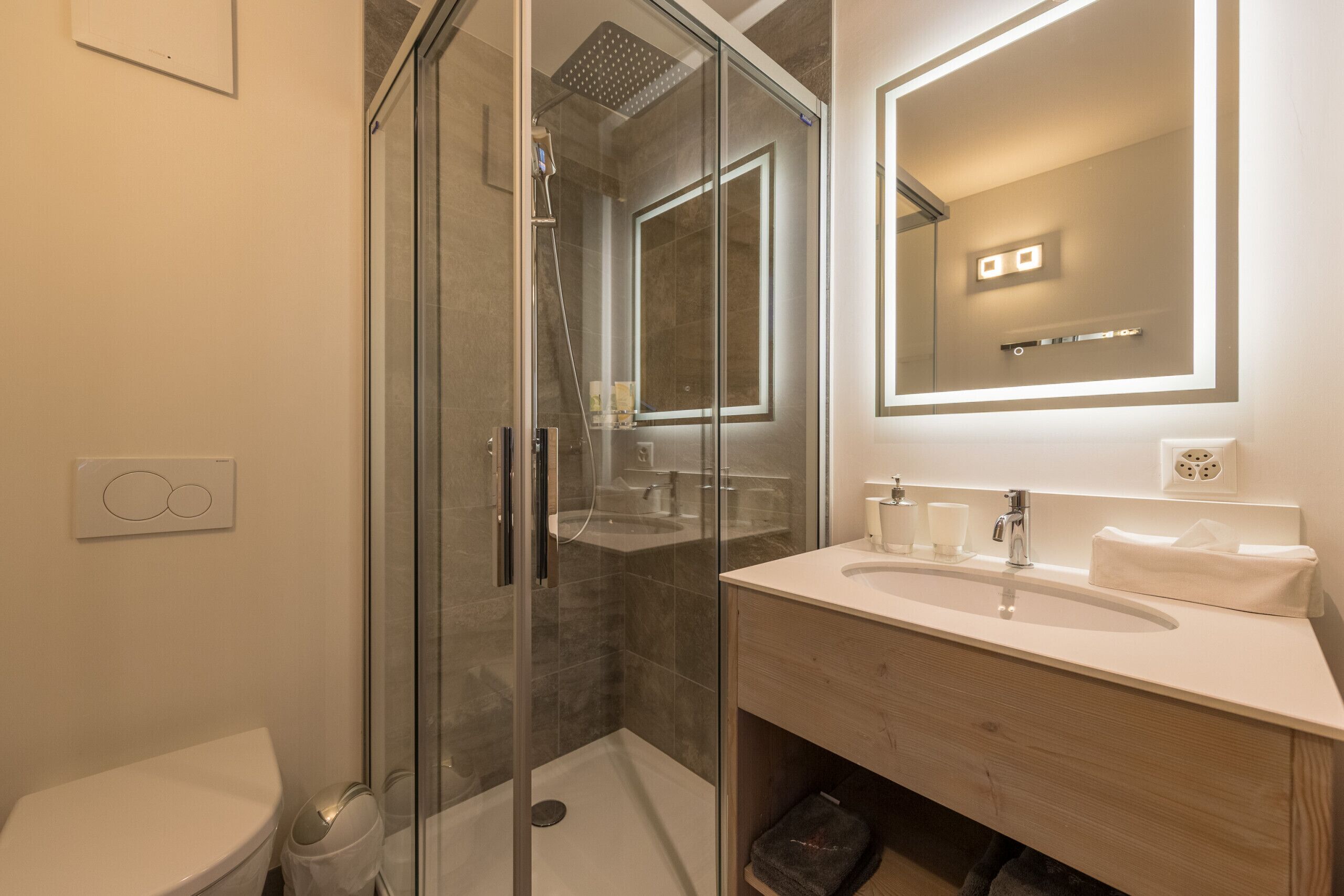 A modern bathroom with a glass-enclosed shower, a wooden vanity, and a large mirror.