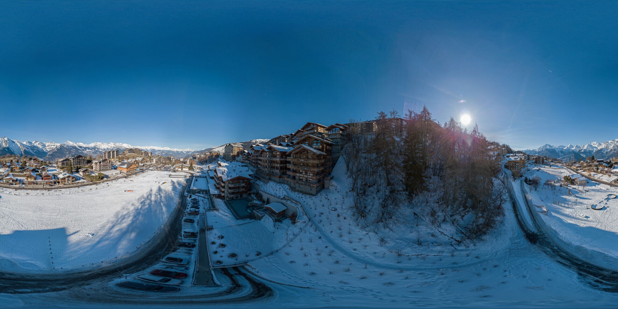 Vista panorámica de un balneario montañoso cubierto de nieve, con edificios y una pista de esquí.