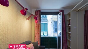 A compact living space with a sofa, a desk, and a view through a glass door to an outdoor area. - Design in Genoa city center by Wonderful Italy (Genova)