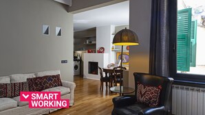 A modern living room with a sofa, a black leather chair, a dining table, and a kitchen in the background. - Design in Genoa city center by Wonderful Italy (Genova)