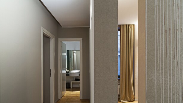 A hallway with wooden flooring, a white door, and a bathroom visible in the distance. - Design in Genoa city center by Wonderful Italy (Genova)