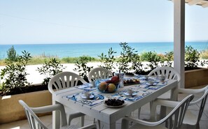 Enjoy a meal with a view of the sea from this outdoor dining area, surrounded by lush greenery and a white fence.