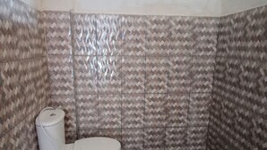 A bathroom with patterned tiles, a toilet, and a stone floor.