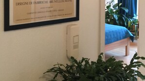 A framed architectural drawing on a wall, a bed with a blue cover, and a potted plant. - bright apartment in the lively, cultural city of Mainz (Rheinland-Pfalz)