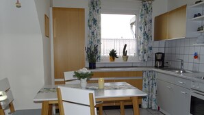 A kitchen with a dining table, chairs, a coffee maker, and a window with curtains. - bright apartment in the lively, cultural city of Mainz (Rheinland-Pfalz)