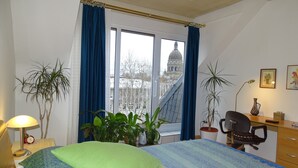 A bedroom with a bed, a desk, a chair, and two potted plants. - bright apartment in the lively, cultural city of Mainz (Rheinland-Pfalz)