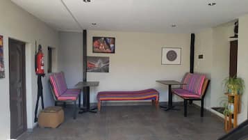 Un espace intérieur spacieux comprenant deux chaises et un banc, un extincteur et un tableau encadré accroché au mur.