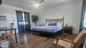 Un dormitorio con cama, escritorio, silla y ventilador de techo.