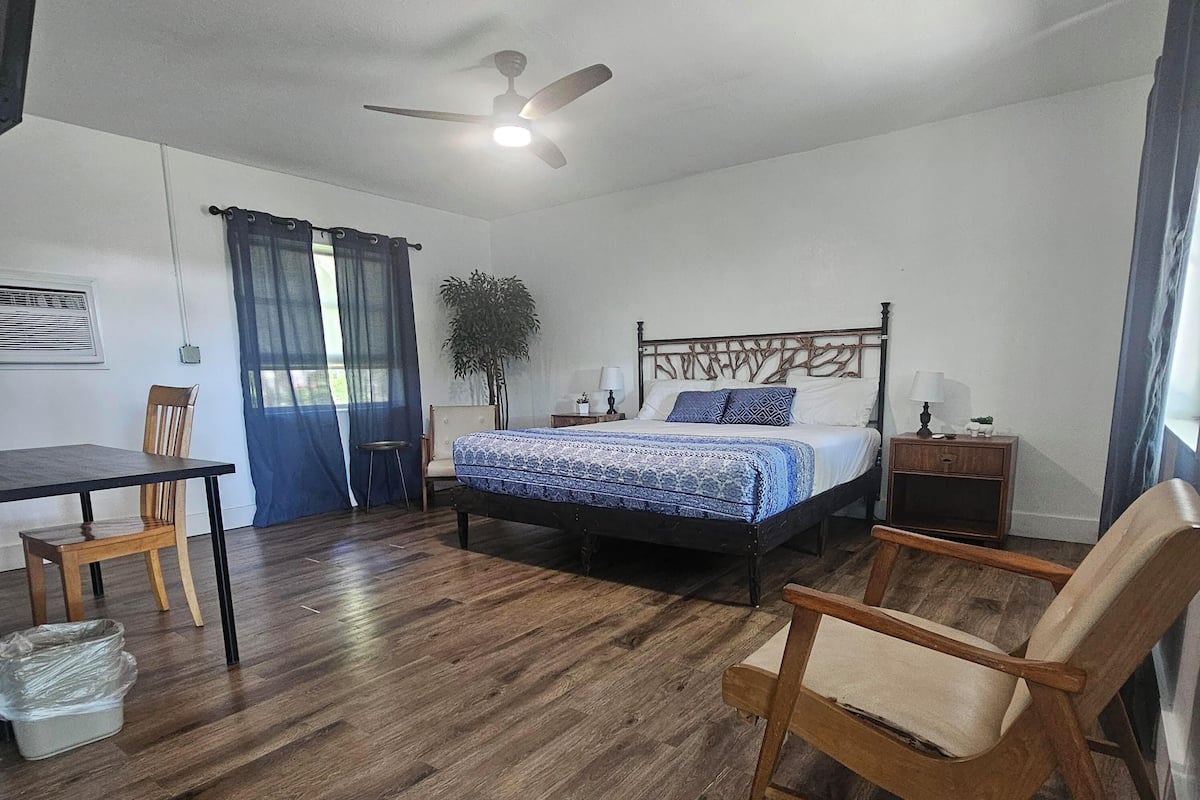 A bedroom with a bed, a desk, a chair, and a ceiling fan.