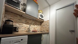 A compact kitchen with a dishwasher, a coffee maker, a microwave, and a toaster.