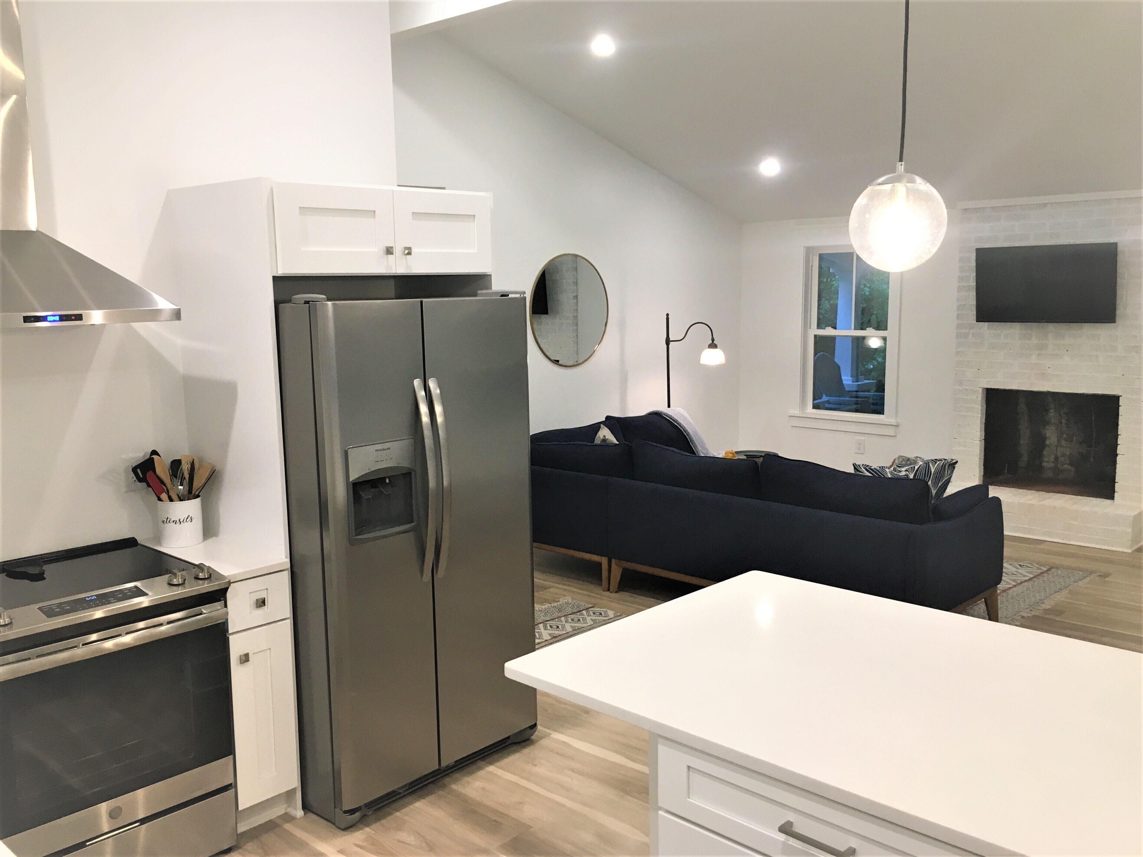 A modern kitchen with a stainless steel refrigerator, oven, and a white countertop.