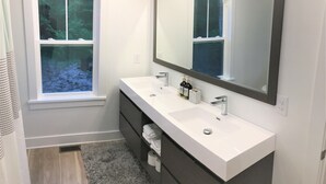 Une salle de bain avec un double vasque, un grand miroir et une fenêtre.