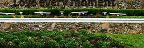 Un muro de piedra con un banco y un parterre de flores.