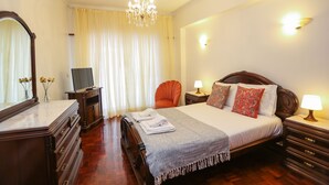 A hotel room with a large bed, wooden furniture, a chandelier, and a television. - Wide and bright Apt (Lisboa)