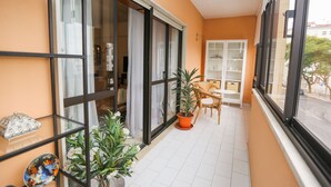 A balcony with a potted plant, a table, and chairs. - Wide and bright Apt (Lisboa)